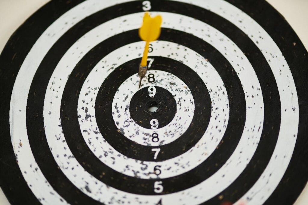 Close-up of a dart hitting the bullseye on a black and white target board symbolizing success.